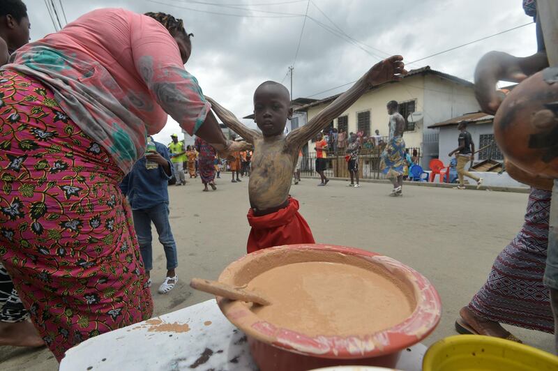 A woman prepares child of the "Blessoue Djehou generation" in initiation  in a street of Adjame village in Abidjan during the "Fatchue" ceremony.  / AFP / SIA KAMBOU