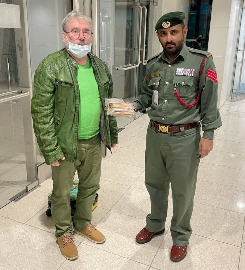 A police officer returns €33,600 (Dh140,000) to German traveller Siegfried Tellbach after he lost the money at Dubai International Airport. Photo: Dubai Police