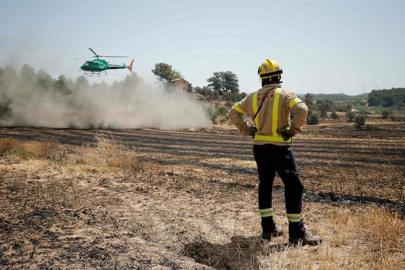 A firefighter looks at an helicopter as they try to extinguish a fire near Flix. AFP