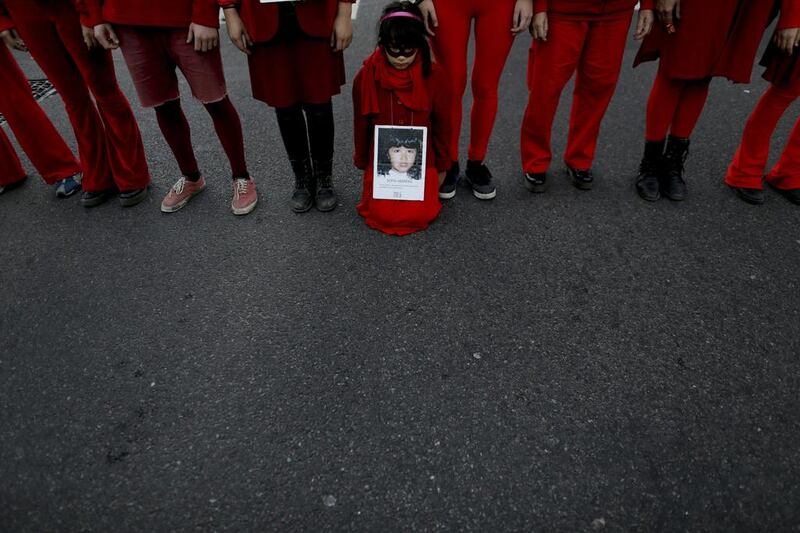 A child holds a picture of a victim of gender violence in Buenos Aires, Argentina. Natacha Pisarenko / AP Photo
