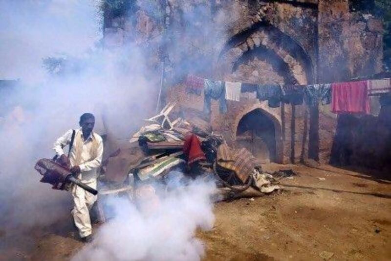 A worker fumigates an area near a monument to prevent mosquitos from breeding in New Delhi.