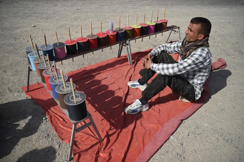 A string vendor waits for customers during a kite battle.