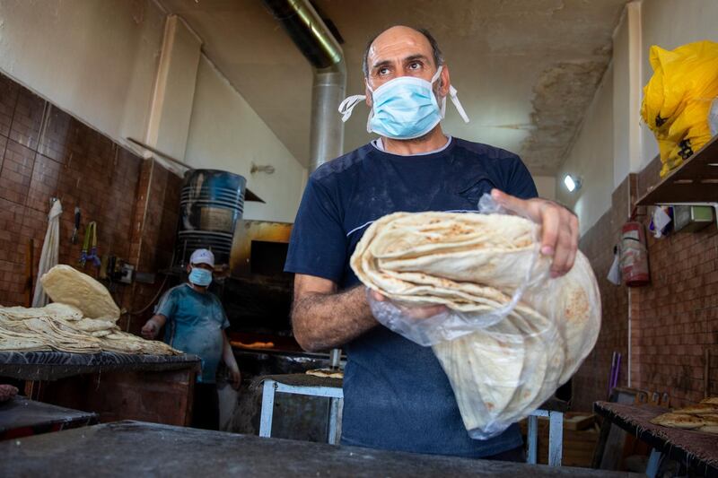 A worker wearing a protective face mask prepares bread for sale at a bakery in Al Ramtha, about 70 kilometres north of Amman, near the Syrian border.  EPA