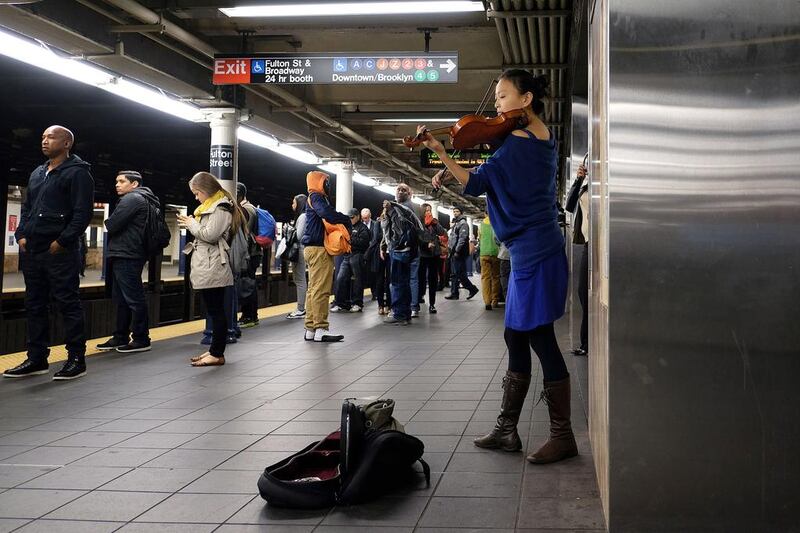 A musician plays a violin as commuters wait to catch their train at the Fulton Center. Jewel Samad / AFP