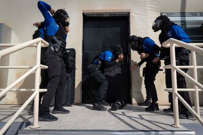 Dubai Police's all-female Swat team try to knock down a door in a hostage-like situation. Antonie Robertson / The National


