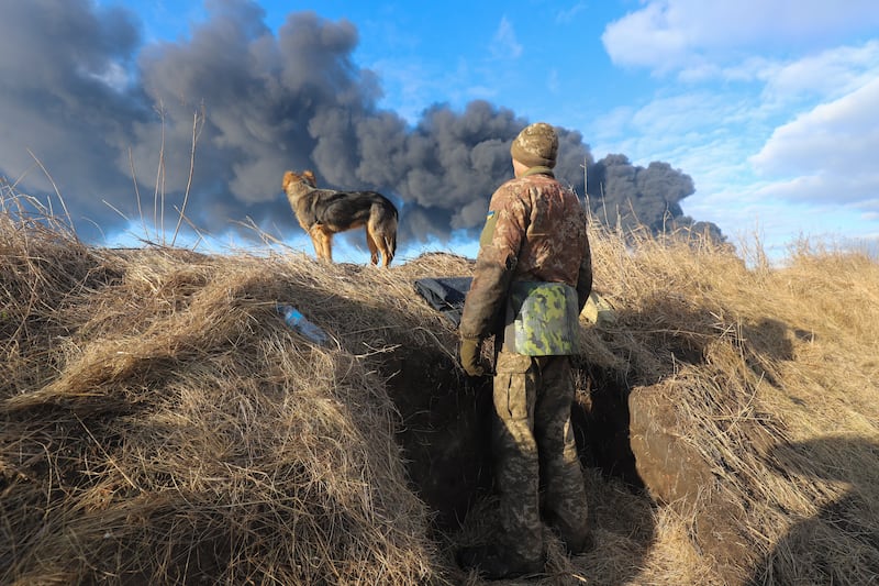 A Ukrainian serviceman and his dog look at smoke from a burning fuel storage depot after a Russian missile attack near Kiev. EPA