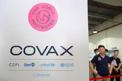 epa09109888 People stand next to a COVAX sign at Noi Bai international airport in Hanoi, Vietnam, 01 April 2021. Vietnam has received the first batch of AstraZeneca/Vaxzevira vaccine through Covax initiative on 01 April 2021.  EPA/LUONG THAI LINH
