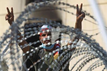 An Iraqi protester flashes the victory sign from behind barbed wire near Baghdad. AFP