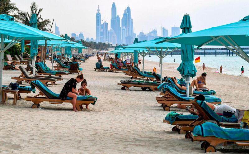 Beach-goers lie on lounge chairs by the shoreline at the Jumeirah al-Naseem beach in Dubai on May 20, 2020, as COVID-19 coronavirus pandemic lockdown measures are eased in the Gulf emirate.  / AFP / Karim SAHIB
