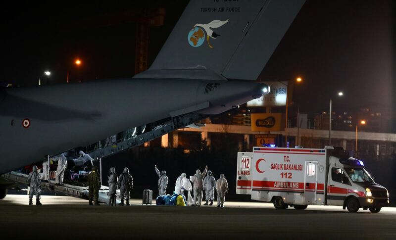 Turkish, Azeri and Georgian evacuees dressed in protective suits and wearing masks leave a Turkish military cargo plane as they are flanked by medical workers upon their arrival from China's Wuhan in Ankara, Turkey. Reuters