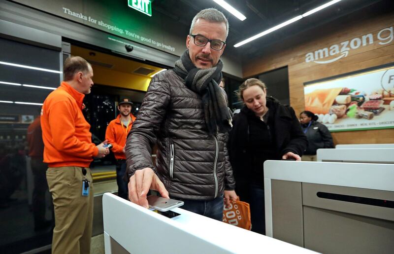 FILE- In this Jan. 22, 2018, file photo a customer scans his Amazon Go cellphone app at the entrance as he heads into an Amazon Go store in Seattle. New Jersey Gov. Phil Murphy has signed legislation barring cashless stores. The new law takes effect immediately and would punish businesses that violate it with a fine of up to $2,500. (AP Photo/Elaine Thompson, File)