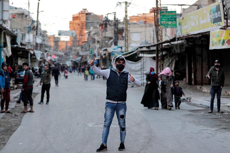 A mask-clad man gestures as he stands in the middle of a street while behind people walk past shuttered shops and stalls in Souk Sabra in the southern suburbs of the Lebanon's capital Beirut, despite a national total lockdown as a measure against the COVID-19 coronavirus pandemic.  AFP