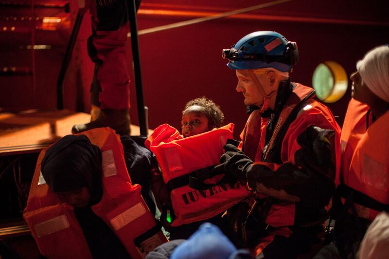 Rescue staff members evacuate a child, as a group of migrants are transferred on December 26 2017, from the Spanish war ship Santa Maria to the non-governmental organization (NGO) Aquarius ship by SOS Mediterranee and Medecins sans Frontieres (MSF - Doctors Without Borders) NGOs.
Some 255 migrants were rescued overnight in the Mediterranean off the coast of Libya, just before a front of bad weather hit the area. The Spanish NGO Proactiva Open Arms picked up a rubber dinghy carrying 134 people, A military ship from the European anti-smuggling operation Sophia also rescued 121 people aboard two other boats. / AFP PHOTO / FEDERICO SCOPPA