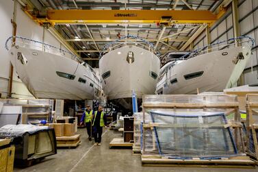 Employees pass by three under-construction Princess Y85 motor yachts in the boat shed at the Princess Yachts Newport Street site in Plymouth, U.K., on Tuesday, March 12, 2019. The current economic climate, with a growing class of super-rich, has been good for the yacht trade, and Princess, which earned almost £30 million ($36 million) on revenue of some £340 million in 2018, has been among the lucky beneficiaries. Photographer: Luke MacGregor/Bloomberg