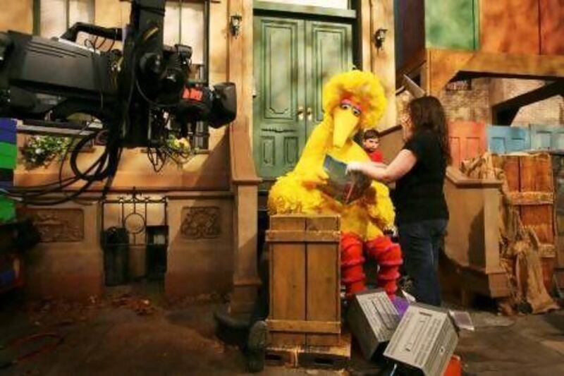 Michelle Hickey, a Muppet wrangler, helps Big Bird hold a book during a rehearsal of Sesame Street in New York.