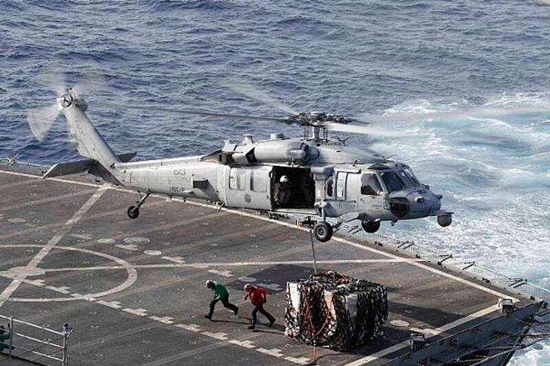 In this Sunday, May 19, 2019 photo, an MH-60S Sea Hawk helicopter transports cargo from the fast combat support ship USNS Arctic to the Nimitz-class aircraft carrier USS Abraham Lincoln during a replenishment-at-sea operation in the Arabian Sea, as Mideast tensions remain high between Tehran and the United States. (Mass Communication Specialist 3rd Class Darion Chanelle Triplett/U.S. Navy via AP)