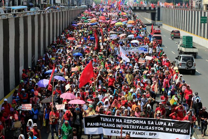 Filipinos from various workers’ groups hold a banner which reads “implementation of national industrialisation and real land reform” during a march in Manila. Romeo Ranoco / Reuters
