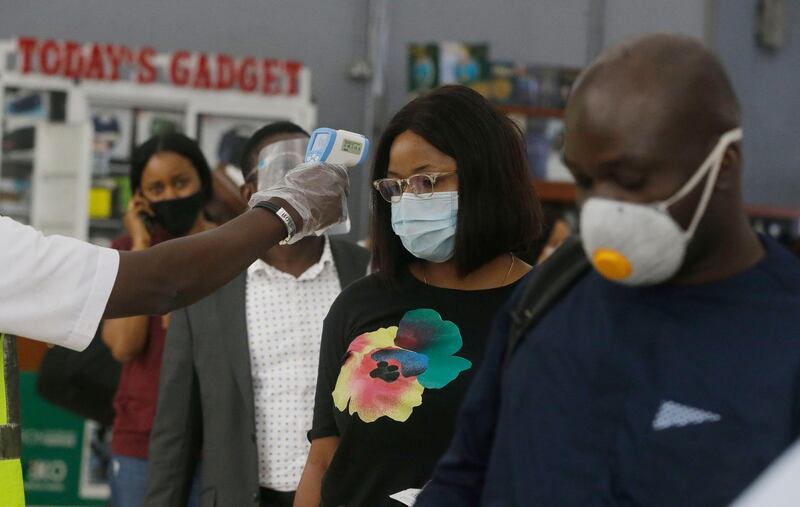 An official from Arik Airline, left, takes temperatures of passengers wearing face masks to protect against coronavirus in the departure hall off the Murtala Mohammed Airport in Lagos. AP Photo