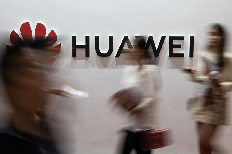 (FILES) In this file photo taken on August 2, 2019 people walk past a Huawei logo during the Consumer Electronics Expo in Beijing.  Huawei was hit February 13, 2020 with new US criminal charges alleging the Chinese tech giant engaged in a "decades-long" effort to steal trade secrets from American companies.A US indictment unsealed in New York alleges Huawei conspired "to misappropriate intellectual property" from six US firms as part of a strategy to grow its global business. / AFP / Fred DUFOUR
