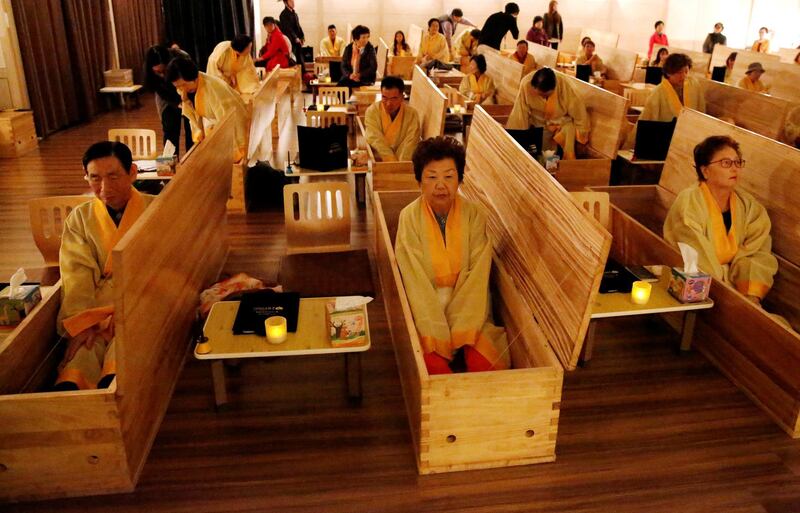 Participants sit inside coffins during a "living funeral" event as part of a "dying well" programme, in Seoul, South Korea. Reuters