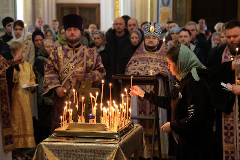 A woman places a lit candle as people attend a memorial service at the Alexander Nevsky Cathedral in Simferopol, Crimea. AFP