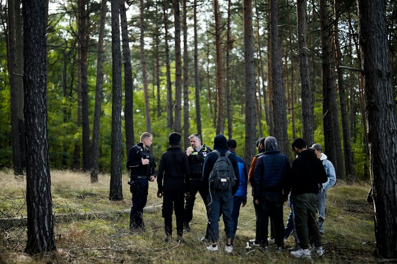 A Federal Police officer and a colleague in a forest near Forst, south-east of Berlin, with a group of migrants who illegally crossed the border from Poland into Germany. AP