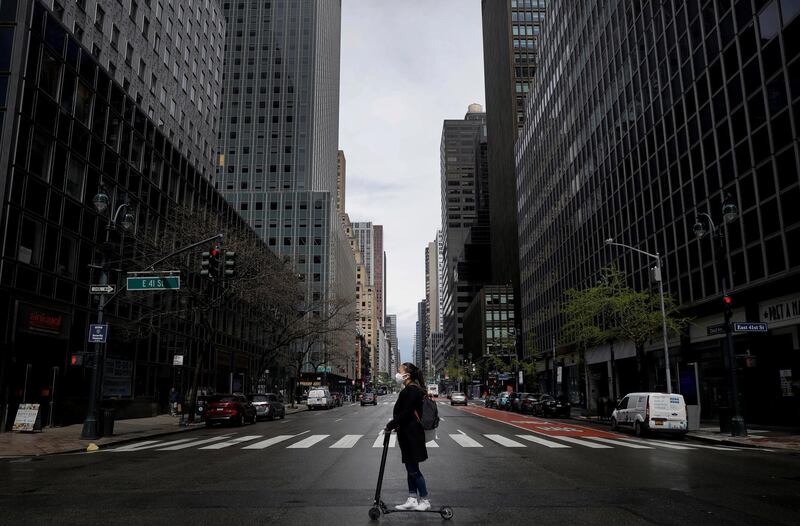 A woman wearing a protective face mask rides a scooter across a nearly empty 3rd Avenue in midtown Manhattan during the outbreak of the coronavirus disease (COVID-19) in New York City, New York, U.S. REUTERS
