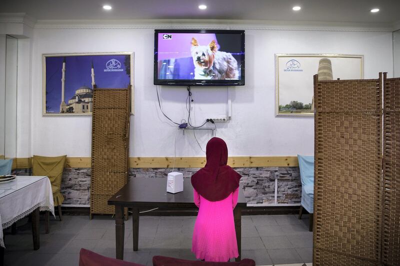 An Uyghur girl watches cartoon at a Uyghur restaurant’s family part.There is huge number of Uyghur community lives in Zeytinburnu district of Istanbul.Thye opened their restaurants,butchers,phone stores around the district.