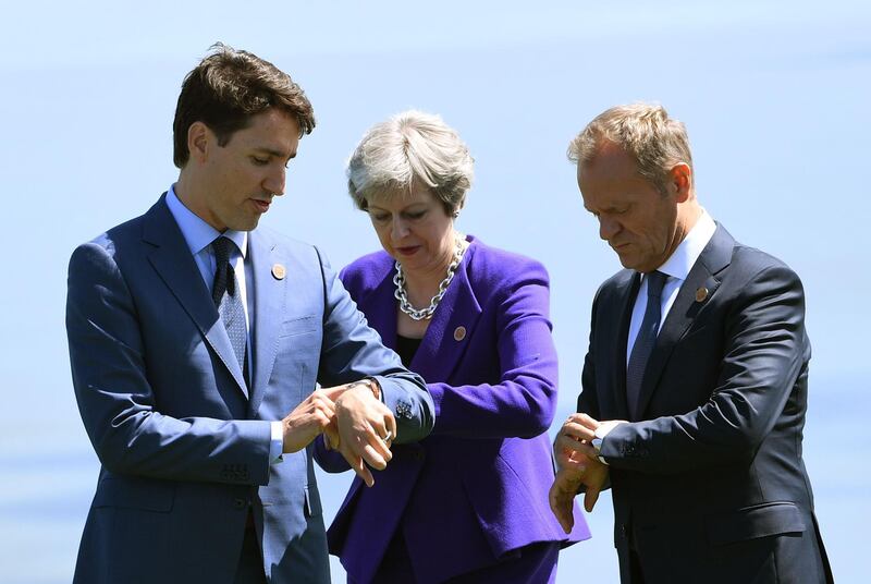 Canadian Prime Minister Justin Trudeau, British Prime Minister Theresa May and the President of the European Council Donald Tusk check their watches after a group photo at the G7 Summit in La Malbaie, Quebec, Canada. Saul Loeb / AFP