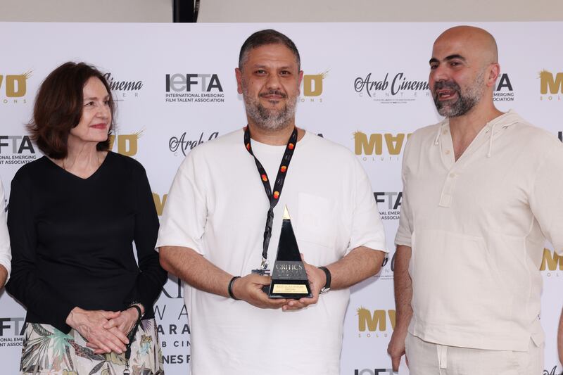 Ahmed Amer, centre, receives an award on stage.