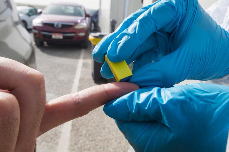 Dubai, United Arab Emirates - A passenger inside the car being tested by pricking blood sample before entering the Abu Dhabi at the new DPI Testing Centres border of Dubai and Abu Dhabi.  Leslie Pableo for The National for Shireena Al Nowais story