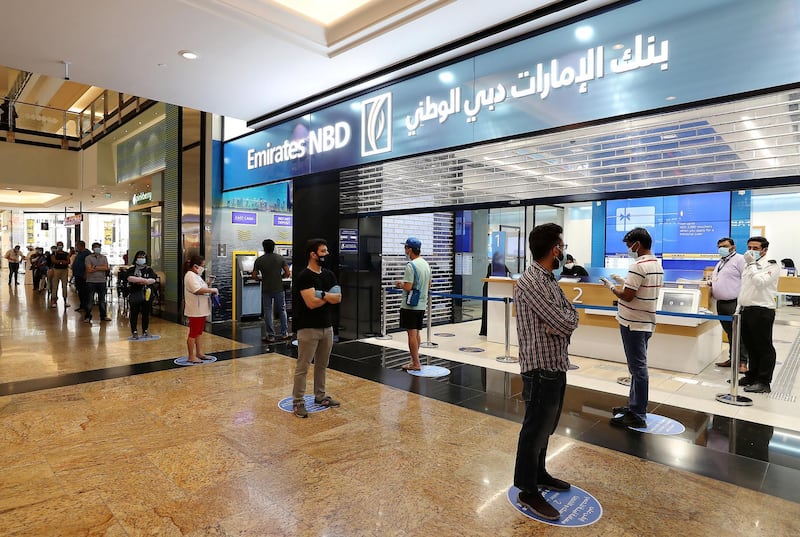 DUBAI, UNITED ARAB EMIRATES , April 29 – 2020 :- People standing in a queue at the Emirates NBD bank and wearing protective face mask and gloves to prevent the spread of the coronavirus at Mall of the Emirates in Dubai. Authorities ease the restriction for the residents in Dubai. At present mall opening timing is 12:00 pm to 10:00 pm. Carrefour timing is 9:00 am to 10:00 pm. (Pawan Singh / The National) For News/Standalone/Online. Story by Patrick