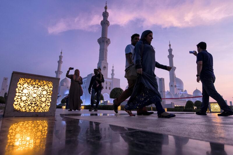 Abu Dhabi, United Arab Emirates, August 31, 2017:    Tourists walk past Sheikh Zayed Grand Mosque as the sun sets ahead of Eid al-Adha in Abu Dhabi on August 31, 2017. Eid al-Adha, or the, Feast of the Sacrifice, honors the willingness of Ibrahim to sacrifice his son Ismaeel, as an act of obedience to God's command. Christopher Pike / The National

Reporter:  N/A
Section: News