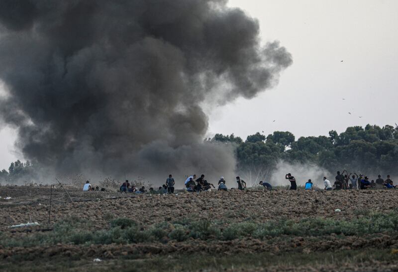 Protesters take cover after Israeli strikes on Friday. Israel says three Hamas sites in Gaza were targeted in response to border riots. EPA