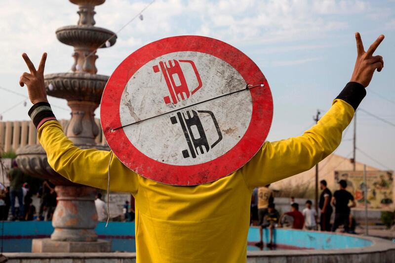 An Iraqi protester wearing a road sign on his head as a means of protection, flashes the victory gesture with his fingers as he takes part in an anti-goverment demonstration in the southern city of Basra. AFP