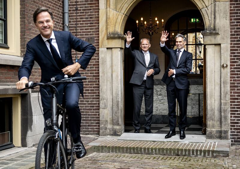 Newly-appointed Dutch Prime Minister Dick Schoof (right) waves to former Prime Minister Mark Rutte (left) leaving on his bike in The Hague. AFP