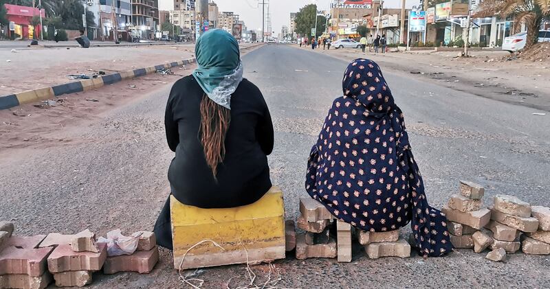 Sudanese women sit on a brick barricade at 60th Street in the capital Khartoum as part of a civil disobedience campaign. AFP