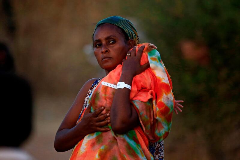 An Ethiopian refugee who fled fighting in Tigray province carries her baby as she walks at the Um Rakuba camp in Sudan's eastern Gedaref province.  AFP