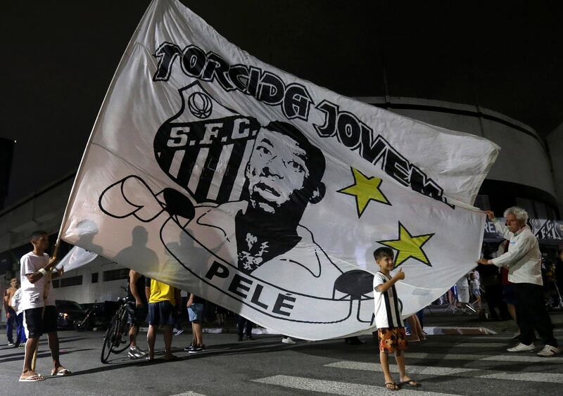 Santos fans wave a flag in tribute to Pele in front of the Vila Belmiro stadium in Santos. EPA