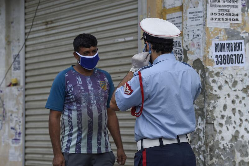 A Bahraini police officer instructs a foreign worker on proper self-protection measures, in the old marketplace of the capital Manama.   AFP