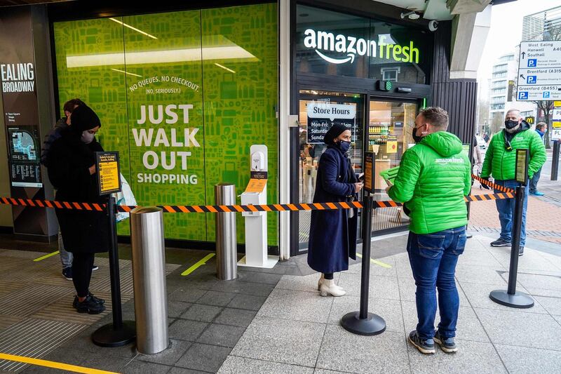 Customers stand socially distanced as they queue to enter Amazon's new Amazon Fresh store. AFP