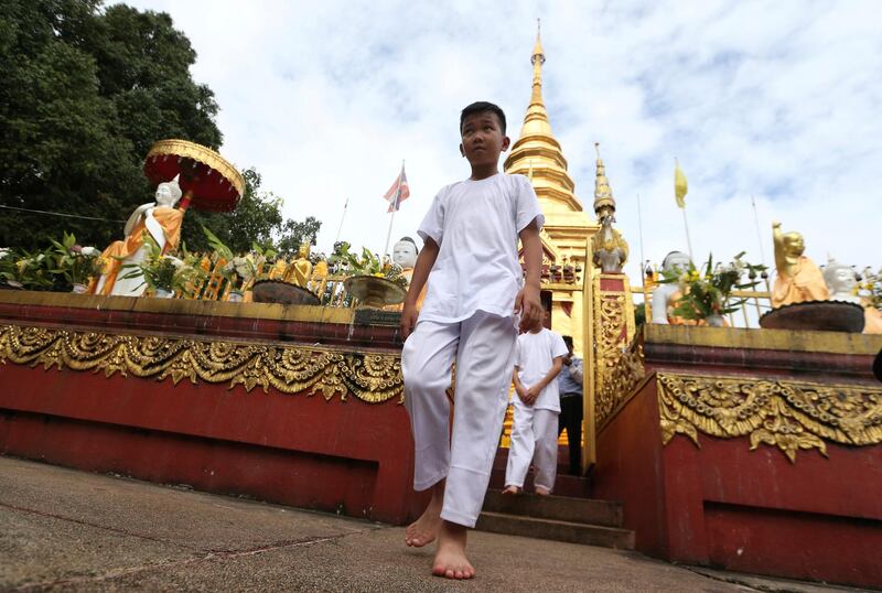 Chanin Vibulrungruang walks with his team members as they attend a Buddhist ceremony. AP Photo