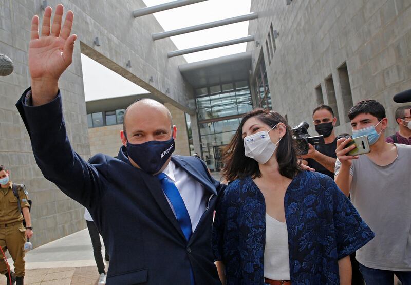 Naftali Bennett, leader of the right wing 'New Right' Yamina party, waves as he walks with his wife Gilat at a polling station where they voted in the city of Raanana. AFP