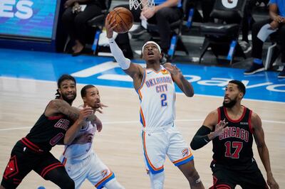 Oklahoma City Thunder guard Shai Gilgeous-Alexander (2) shoots between Chicago Bulls guards Coby White (0) and Garrett Temple (17) and Thunder's George Hill (3) during the second half of an NBA basketball game Friday, Jan. 15, 2021, in Oklahoma City. (AP Photo/Sue Ogrocki)