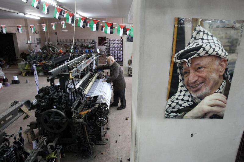 Yasser Al Hirbawi stands behind a portrait of Yasser Arafat. AFP Photo