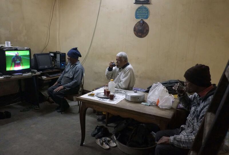From left, brothers Gamal, Hashim and Mahmoud Abdelmeniem drink tea as they watching a football match on television at their house on the rooftop of a building in Cairo. 