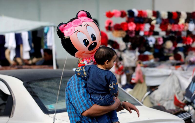 A man carries his son who holds a balloon outside a shopping centre in Sanaa.  Reuters