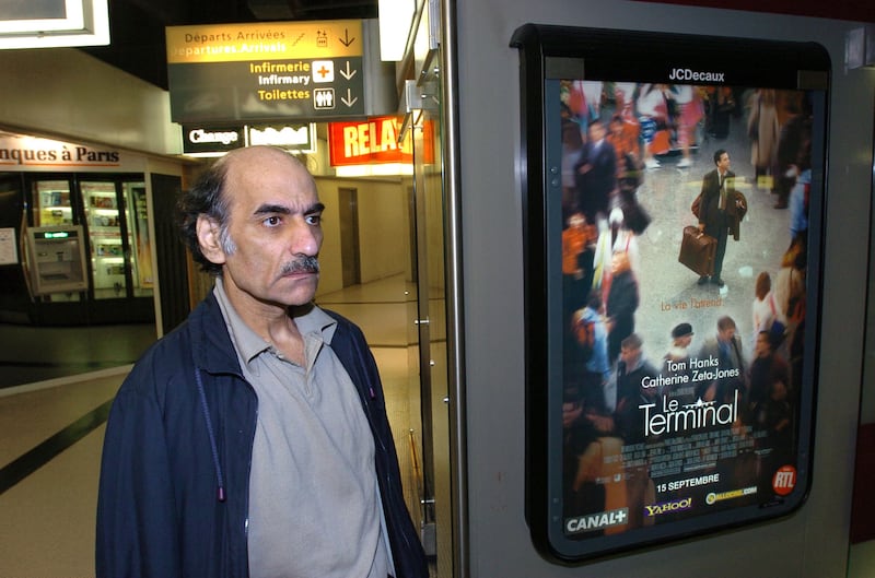 Mehran Karimi Nasseri passes by the poster of the movie inspired by his life, in Terminal 1 of Paris Charles De Gaulle Airport. AFP.