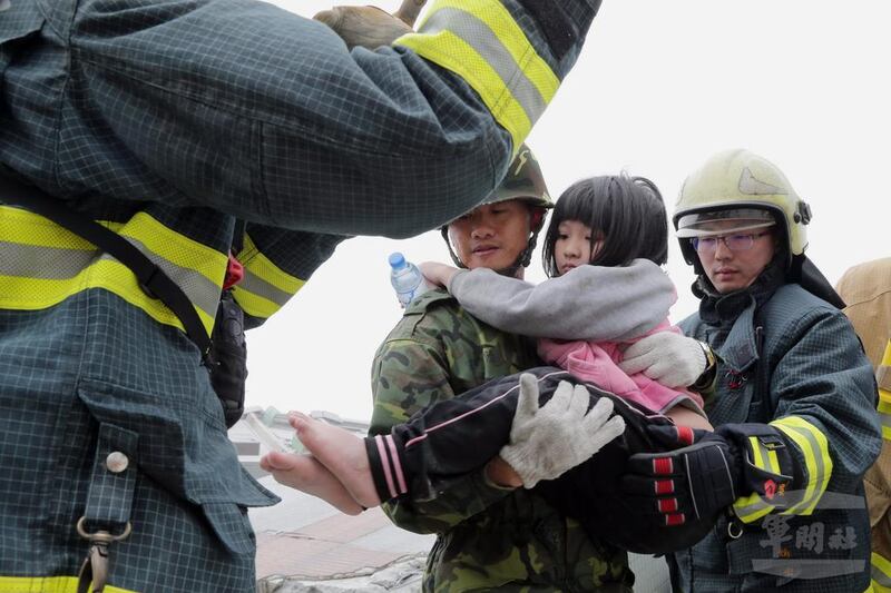 A handout photo released by the Military News Agency shows Taiwanese soldiers holding a young girl resuced from a collapsed building in Tainan, south Taiwan. Military News Agency / EPA