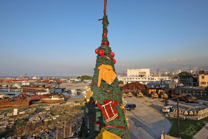 Members of the Lebanese Civil Defense erect a Christmas tree by Lebanese artist Hayat Nazer, decorated with uniforms of firefighters, as a way to pay tribute to colleagues who were killed in the August 4 port explosion, in the Lebanese capital Beirut's harbour, on December 18, 2020. (Photo by ANWAR AMRO / AFP) / “The erroneous mention[s] appearing in the metadata of this photo by ANWAR AMRO has been modified in AFP systems in the following manner: [uniforms of firefighters as a way to pay tribute ] instead of [the uniforms of firefighters who were killed]. Please immediately remove the erroneous mention[s] from all your online services and delete it (them) from your servers. If you have been authorized by AFP to distribute it (them) to third parties, please ensure that the same actions are carried out by them. Failure to promptly comply with these instructions will entail liability on your part for any continued or post notification usage. Therefore we thank you very much for all your attention and prompt action. We are sorry for the inconvenience this notification may cause and remain at your disposal for any further information you may require.”